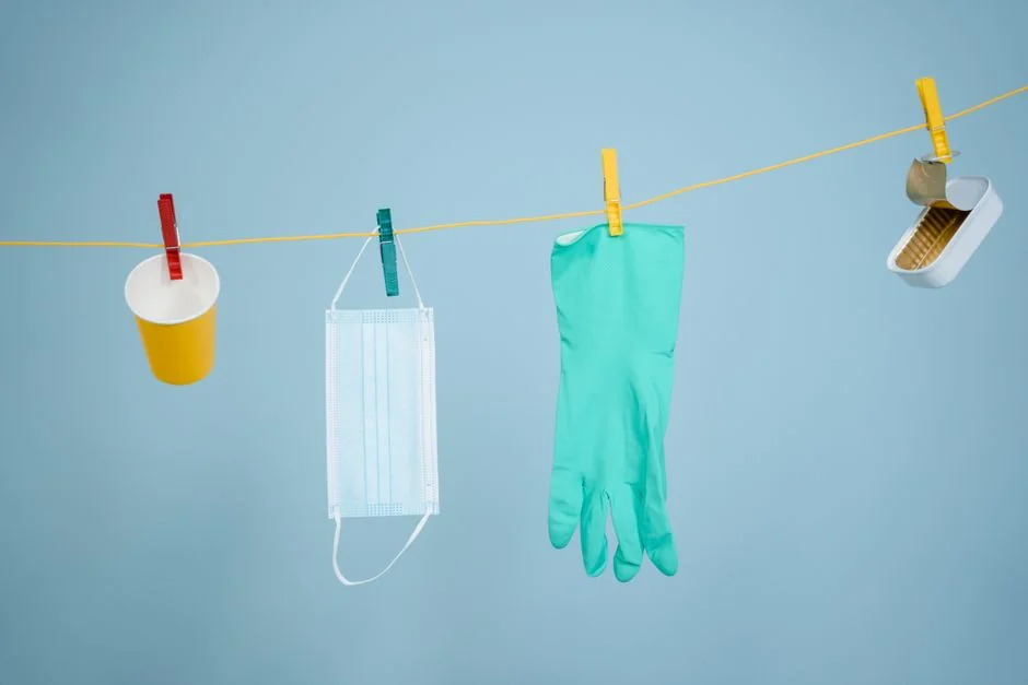 An indoor scene showing a man wiping a glass door with a spray bottle and cloth.